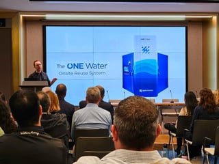 Aaron Tartakovsky on stage at Reuse Summit at the EPA with Epic OneWater system slide in view