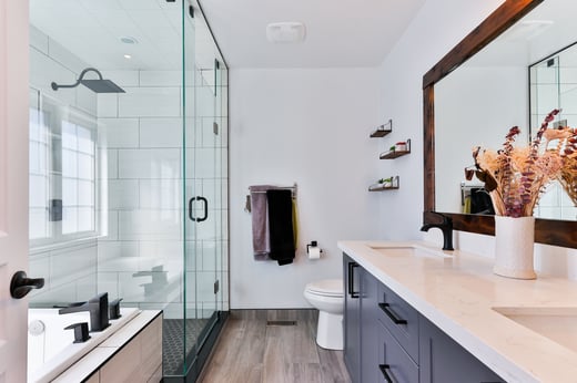 Image of residential bathroom with glass shower, tub, toilet and sink in view.