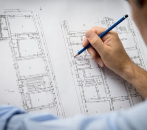 person using pencil to edit a building design